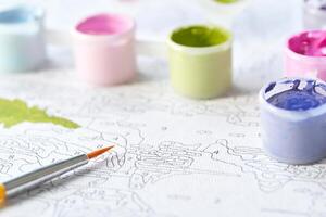 Paint by numbers relaxation art with colorful paint jars and brush on unfinished canvas. photo