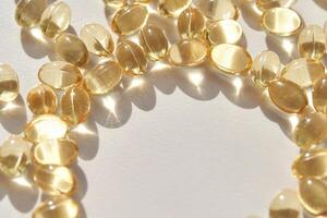 Shiny transparent capsules arranged in circle on white surface with sunlight reflection photo
