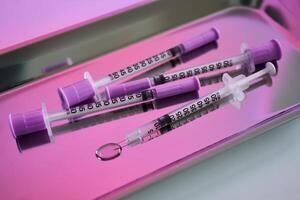 Injection syringes on a medical tray in bright pink color. photo