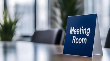 Meeting Room sign on office glass wall with empty collaboration workspace, large table, and armchairs in background. photo