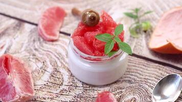 homemade sweet yogurt in a glass jar with pieces of red ripe grapefruit and honey, on a wooden table video