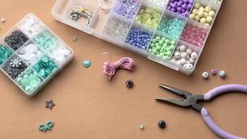 Crafting with colorful beads on a flat workspace with tools and containers in bright daylight video