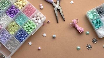 Crafting with colorful beads on a flat workspace with tools and containers in bright daylight video
