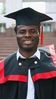 Portrait of smiling student graduate near university. Vertical video