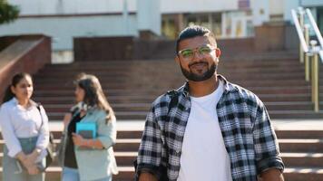 Handsome university Indian student going on a class at the university and looking at camera video