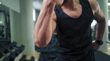 Strong athletic man on mirror background in gym. Muscular man shows his trained biceps on arms while looking at his reflection in the mirror. video