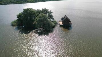 Small island and a house in the middle of the river. Aerial view of beautiful green island surrounded by water. Camera moves round. video