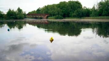 Handmade yellow and blue paper ships are floating on the river in the evening. Two origami boats are sailing on calm river with a little rain falling from the sky into the water. video