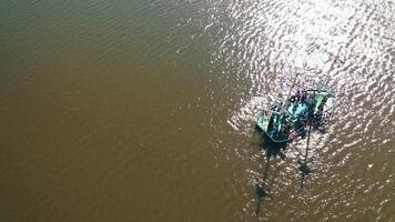 People in a boat on the water background. An old boat floating in the river with sunlight reflections in summer. Aerial view. video