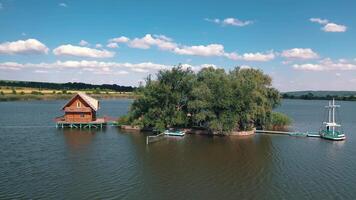 Green island and a house on water. Aerial view of beautiful island in the middle of a lake surrounded by water on the natural background. video