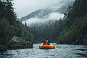 A lone rafter navigates a river surrounded by lush greenery and fog-covered mountains. photo