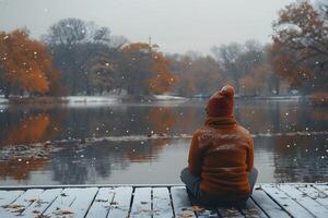 Contemplative Moment by the Lake in Snowy Autumn Setting photo