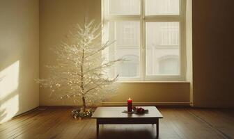 A white Christmas tree sits in front of a window with a candle on a table photo