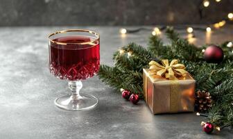A glass of red wine is on a table next to a Christmas tree photo