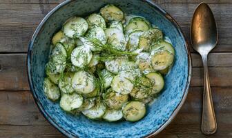 A bowl of cucumbers with a spoon in it photo