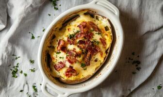 A white bowl with a potato and bacon inside photo