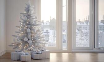 A white Christmas tree with lights and ornaments sits in front of a window photo