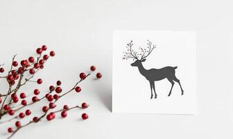 A white card with a deer on it sits on a table with red berries photo