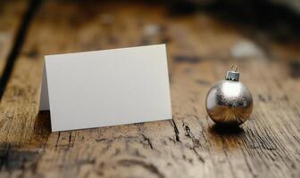 A white card with a name on it sits on a wooden table next to a silver ornament photo