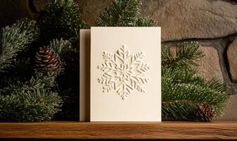 A white card with a snowflake on it sits on a shelf next to a pine tree photo