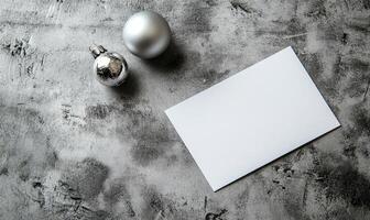 A silver ball and a white card with a blank space sit on a grey surface photo
