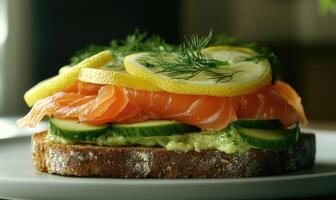 A sandwich with salmon, cucumber, and lemon slices on a white plate photo