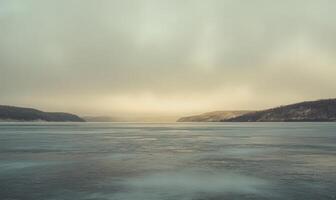 A large body of water with a cloudy sky in the background photo