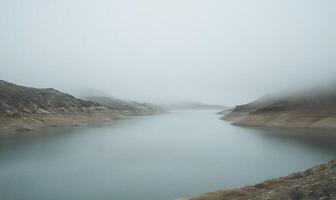 A foggy mountain range with a lake in the foreground photo