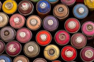 Top view of multiple colorful spray paint cans arranged together, showcasing various shades and worn textures, ideal for art projects. photo