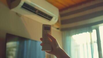 hand holding an air conditioner remote. Air conditioner inside the room with woman operating remote controller photo