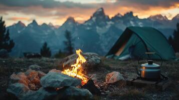 Camp fire and tea pot, tent and mountains in the background at sunset. Travel concept and Hobbies photo