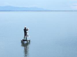 Fisherman catching fish with net on the lake in the morning, Gorontalo, Indonesia photo