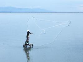 Fisherman catching fish with net on the lake in the morning, Gorontalo, Indonesia photo