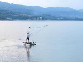 Fisherman catching fish with net on the lake in the morning, Gorontalo, Indonesia photo