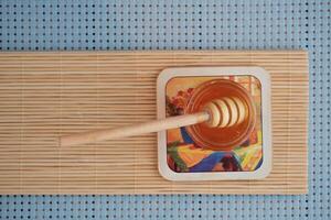 A above view of a organic honey from bees with a wooden honey stick dipper on the wooden table isolated on blue background photo