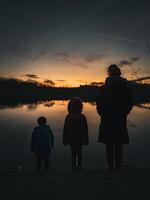 Behind view of a happy family enjoying the views shore at sunset. photo