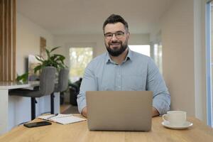 A happy man using a laptop while working at home office. photo