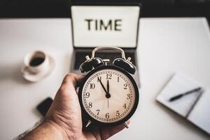 Business working time concept, word time on the laptop screen, notes and a clock on a office desk, stress at work, clock with five minutes to twelve o'clock. photo