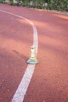 A small lamp sitting on the side of a running track photo