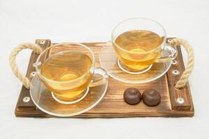 Two cups of tea on a wooden tray with chocolate photo