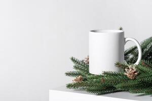 Christmas mockup one white empty tea mug on a white table and branches of a Christmas tree wreath. photo