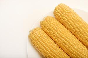 Ripe corn cobs on a white plate. Ripe vegetables. photo
