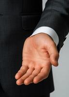 A man in a suit is holding his hand up, possibly to show something to someone. Concept of professionalism and formality, as the man is dressed in a suit and tie photo