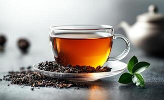A cup of tea with a leaf on top of it. The cup is on a saucer and the leaf is on the table photo