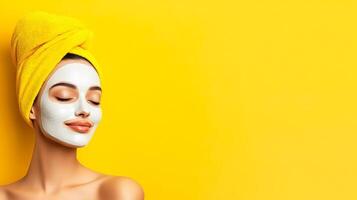 A woman with a white face mask on and a yellow towel on her head. She is smiling and looking at the camera photo