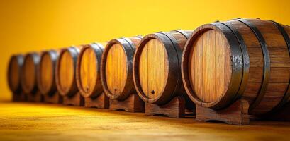 A row of wooden barrels with a yellow background. The barrels are lined up and appear to be empty photo
