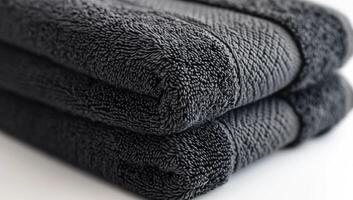 Two black towels are stacked on top of each other. The towels are made of a soft, plush material and have a shiny, smooth texture. Concept of luxury and comfort photo