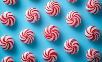A row of red and white candy canes are arranged in a spiral pattern. The candy canes are placed in a blue background, creating a festive and cheerful atmosphere photo