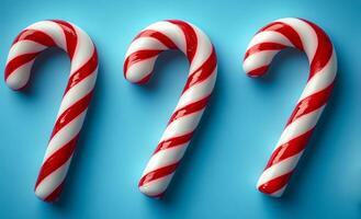 Three red and white candy canes are arranged on a blue background. The candy canes are placed in a row, with one slightly overlapping the other two. The arrangement creates a festive and cheerful mood photo