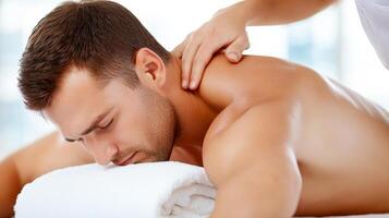 A man is getting a massage on his back. The masseuse is applying pressure to his back photo